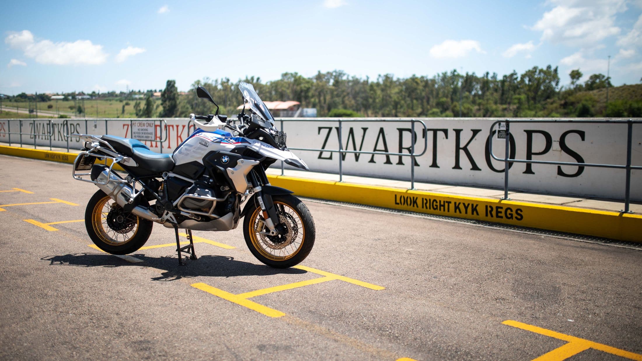 A BMW motorcycle parked beside the Zwartkops trackside barrier